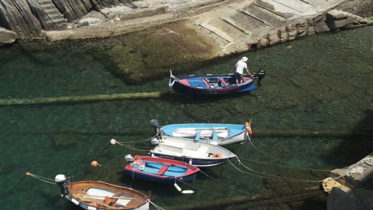 Fisherman with colorful rowboat in the blue sea of Liguria.