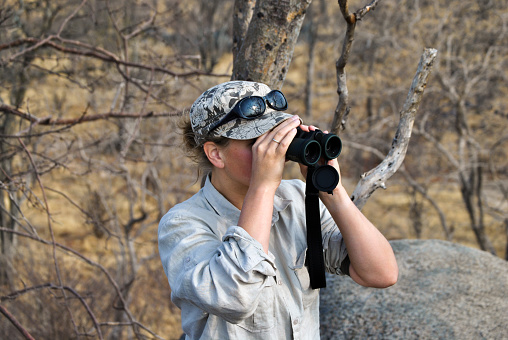 Tourist looking for wildlife through binoculars on a safaritrip