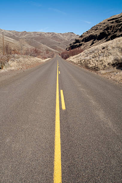 istock Lonely Two Lane Divided Highway Cuts Through Dry Hills Landscape 186196333