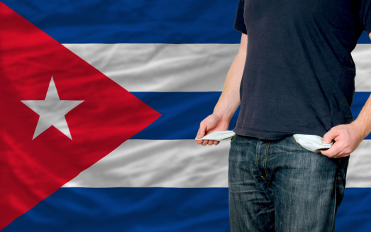 poor man showing empty pockets in front of cuba flag