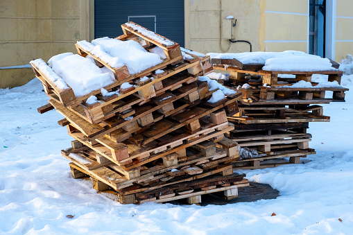 Stack of wooden pallets under snow in a warehouse area