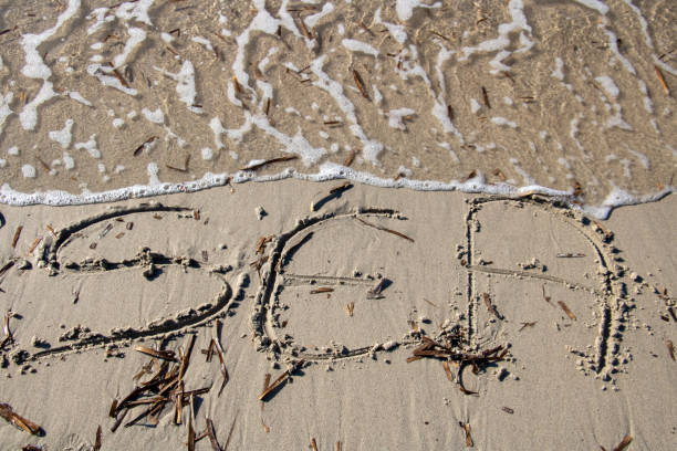 Word sea written on the sand on a beach at the edge of the wave that touches the word and will erase it