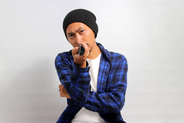 istock Bored young Asian man holding a remote control while watching TV 1862025403