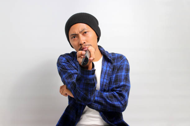 istock Bored young Asian man holding a remote control while watching TV 1862032100