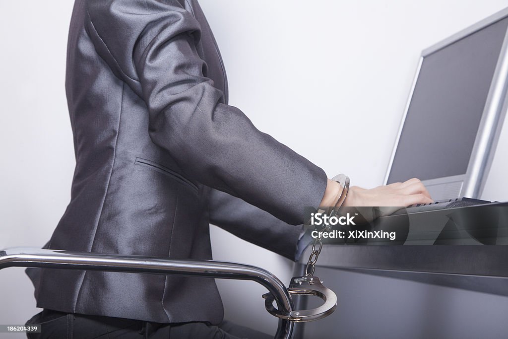 Young businesswoman handcuffed to her office chair 20-24 Years Stock Photo