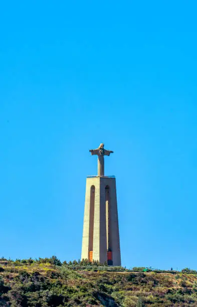 Monumental stone statue of Christ the King Almada of Lisbon (Christus Statue Lissabon) sanctuary dedicated to the Sacred Heart of Jesus of Almada. Clear blue sky.