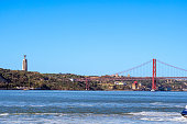 Panoramic view of Lisbon's April 25 steel suspension bridge and the religious monument and sanctuary dedicated to the Sacred Heart of Jesus of Almada from the coast.