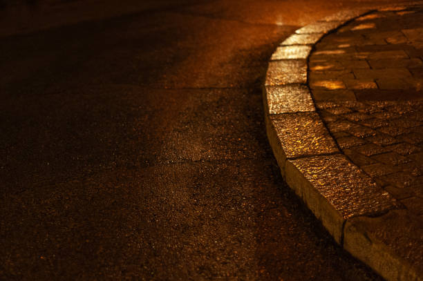 istock Abstract, wet, textured road and sidewalk illuminated at night 1862122068