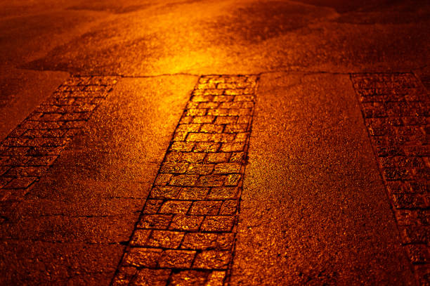 Shiny, colorful, cobblestone streets shimmer with artificial light following a rain storm and create an ideal, abstract texture for background illustration.