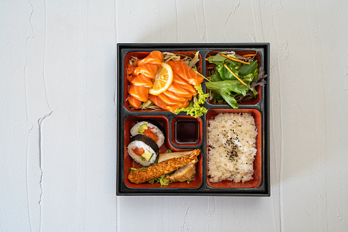 Japanese meal set with a bowl of unagi eel fillets grilled in a kabayaki style topped on steamed rice with sashimi of octopus and tuna fish, suimono clear soup, baked cookies and waribashi chopsticks