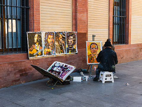 Seville, Spain - December 13, 2023: street artist makes a portrait of a man, on the streets of Seville