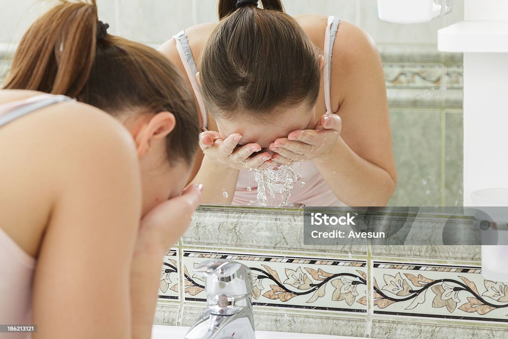 Young woman washing her face with clean water Young woman washing her face with clean water in bathroom Adult Stock Photo