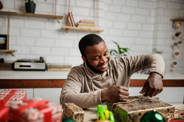 istock Smiling black man wrapping Christmas gifts 1862134232