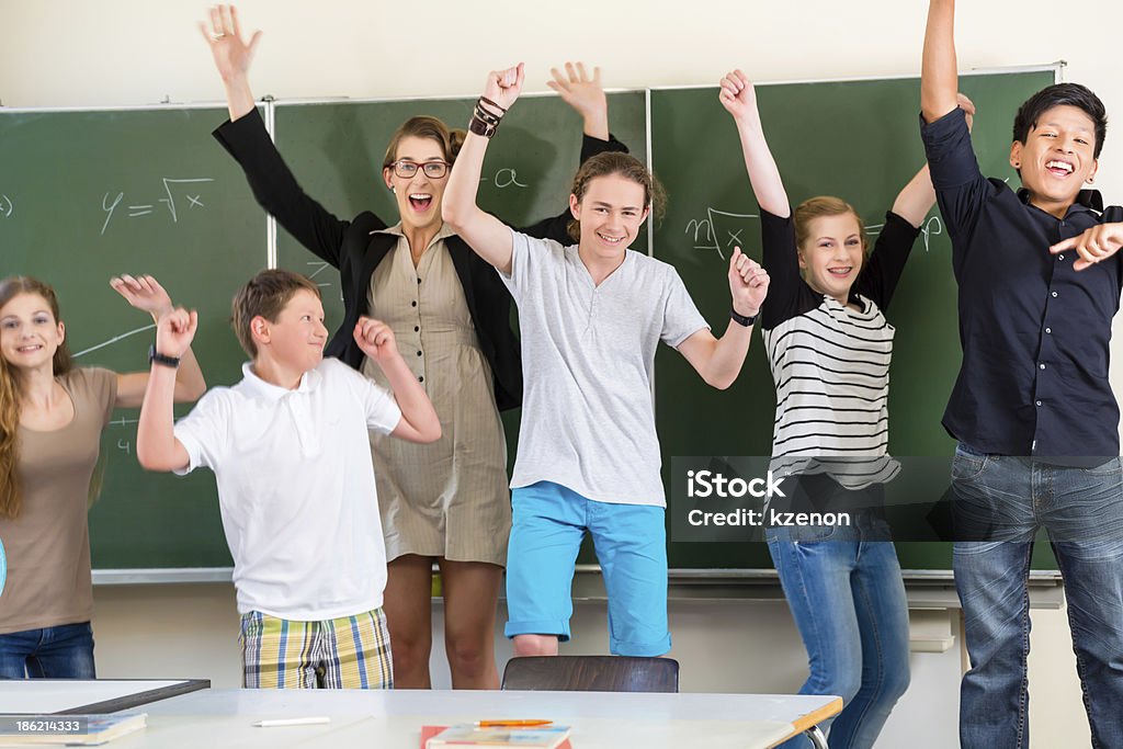 Teacher motivating students in school class Successful Teacher and students jump in front of a blackboard with math work in a classroom or class school while lesson Student Stock Photo