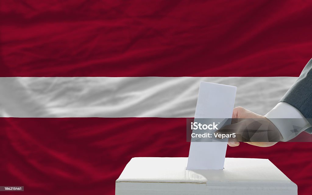 Hombre de voto en las elecciones en frente de bandera de letonia - Foto de stock de Adulto libre de derechos