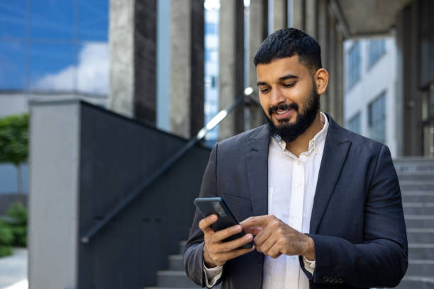istock A young Muslim male businessman is using a mobile phone while standing outside an office center. Close-up photo 1862164861