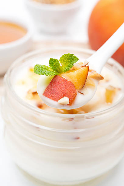 yoghurt with honey, peaches, nuts in a spoon close-up, vertical