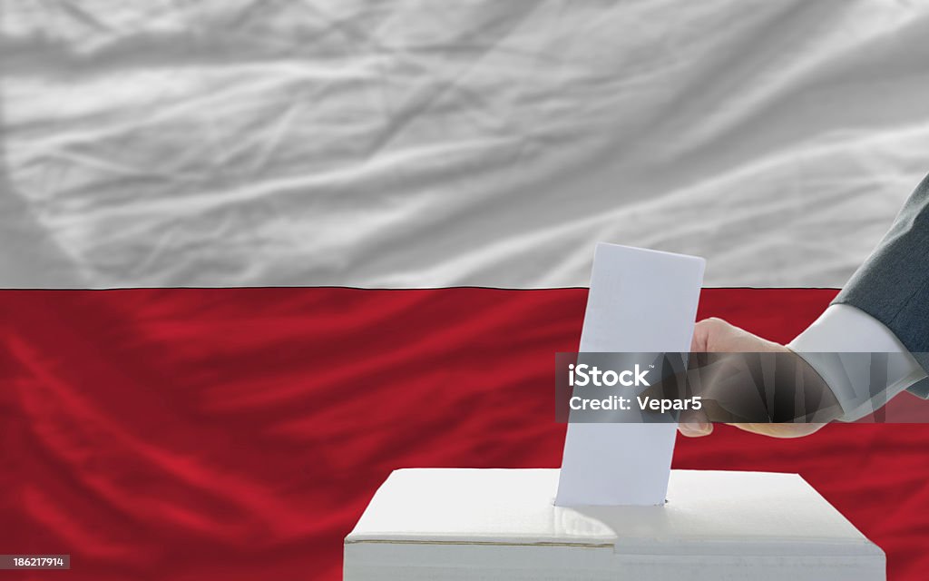 Homem de voto nas eleições na Polônia frente da bandeira - Foto de stock de Polônia royalty-free