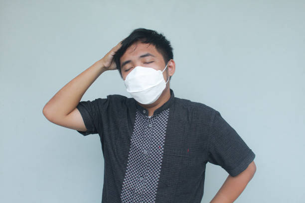 istock Young Asian man wearing mask suffering from headache and flu. 1862189264