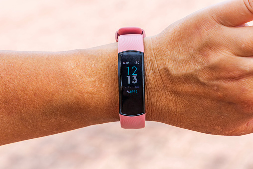 Close-up view of a female hand with smart sports watches displaying a high number of steps, emphasizing an active lifestyle theme.