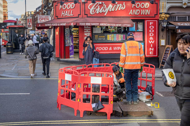 Macclesfield Street, London, England - November 6th 2023:  Workers repairing a phone cable in a manhole in the middle of the street