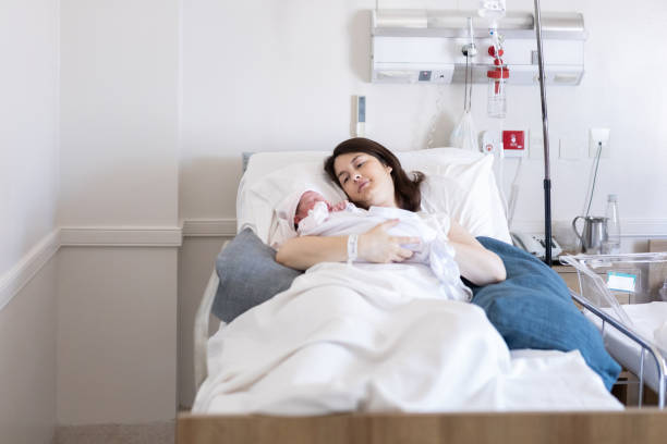 Mother holding her newborn baby at hospital after cesarean section stock photo