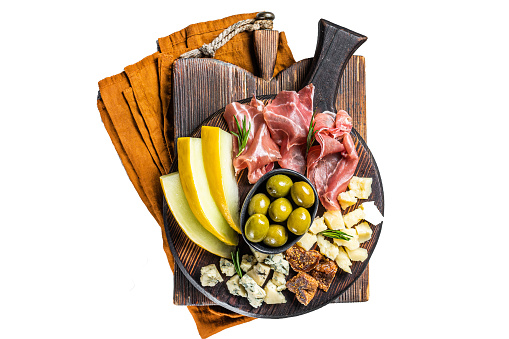 Italian appetizer platter, antipasti snack with Prosciutto ham, Parmesan, Blue cheese, Melon and Olives on wooden board.  Isolated, white background
