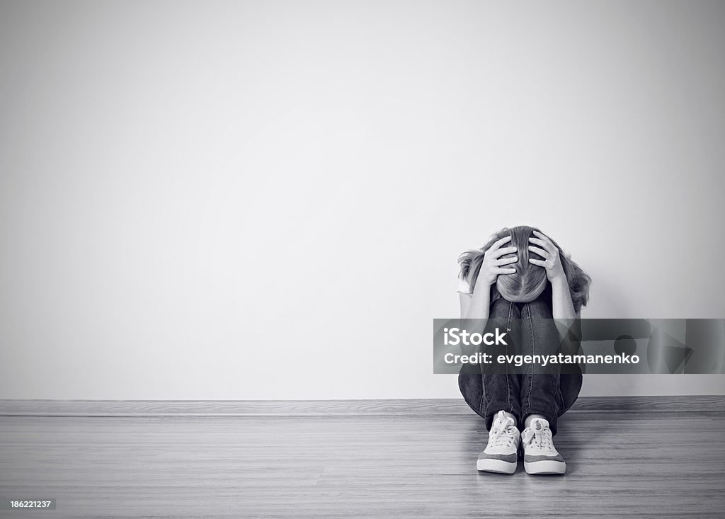 girl sits in a depression on the floor near  wall girl sits in a depression on the floor near the wall monochrome Black Color Stock Photo