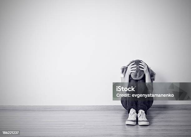 Girl Sits In A Depression On The Floor Near Wall Stock Photo - Download Image Now - Black Color, Problems, Teenager