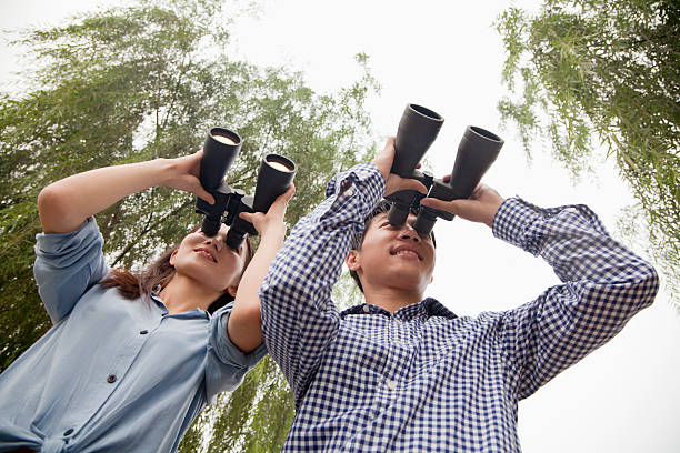 jovem casal olhando em binóculos - young men looking up thinking looking - fotografias e filmes do acervo