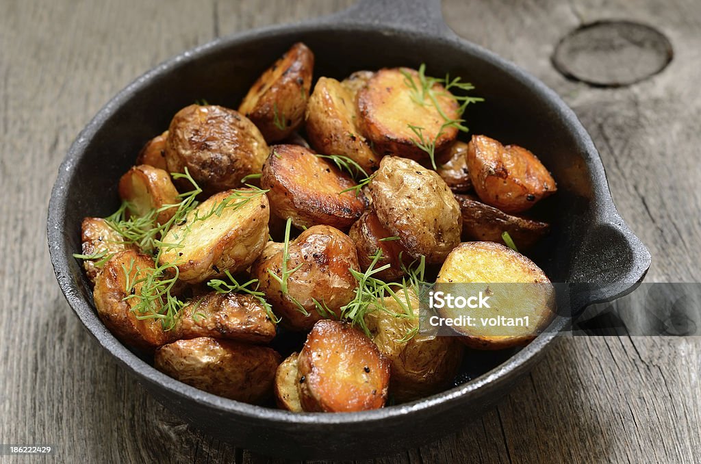 Roasted potato Roasted potato in a frying pan on wooden table American Culture Stock Photo