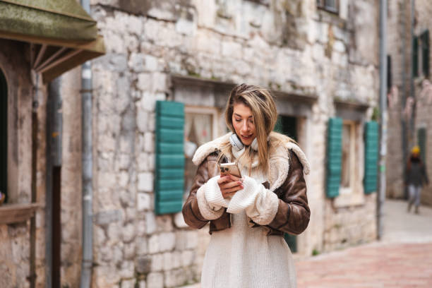 istock Beautiful young blonde woman using her smart phone while walking around the old town Kotor, Montenegro 1862235721