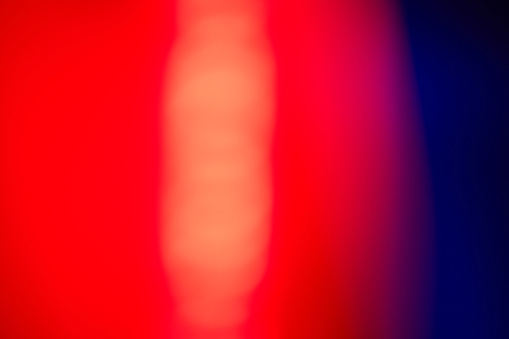Abstract defocused lens red light leak on blue background.