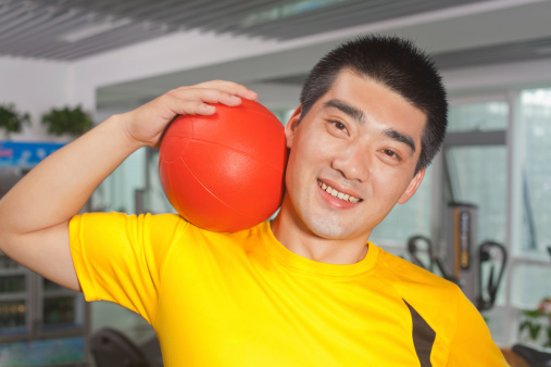 Man with ball on his shoulder in the gym