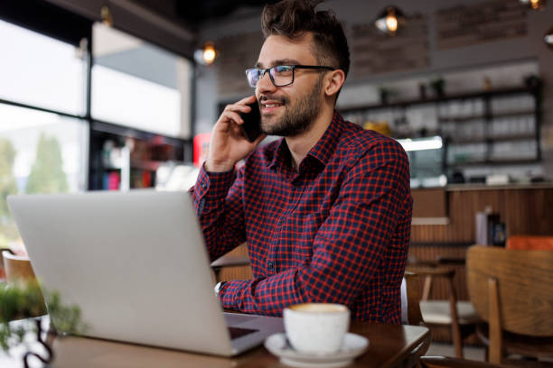 istock Young smiling businessman talking on a mobile phone at cafe 1862277856