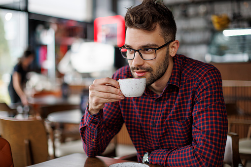 Young atractive man drinking coffee at a cafe