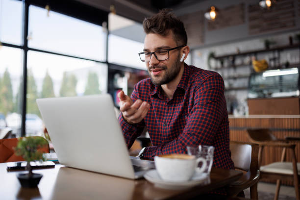 istock Smiling young man with headphones using laptop at a cafe 1862277893