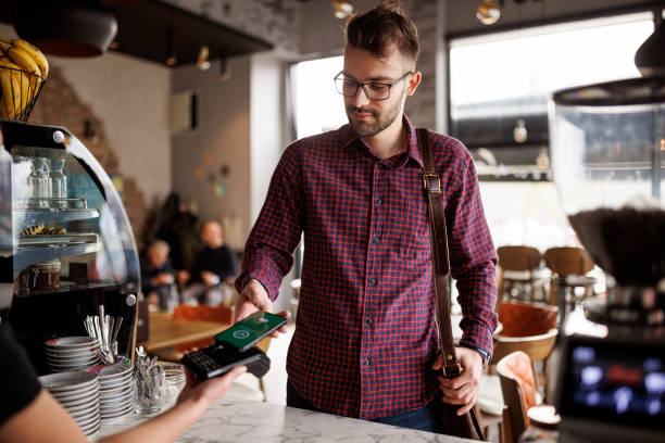 istock Young man making contactless payment with smartphone at a cafe 1862277894