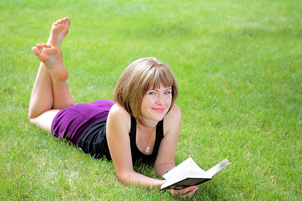 Girl with blonde hair reading a book in the park