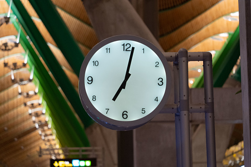 London, England-August 2022; View of the large analog clock on the platform of Kings Cross station with brick side of concourse and steel beams of the roof of the station