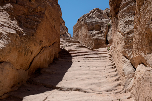A staircase carved out of rock at the Petra archeological site. Petra is a world famous archeological site in Jordan. Petra is half-built, half-carved into the rock, and is surrounded by mountains riddled with passages and gorges. Also known as the \