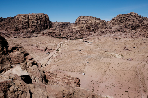 An aerial view of the Petra archeological site. Petra is a world famous archeological site in Jordan. Petra is half-built, half-carved into the rock, and is surrounded by mountains riddled with passages and gorges. Also known as the \