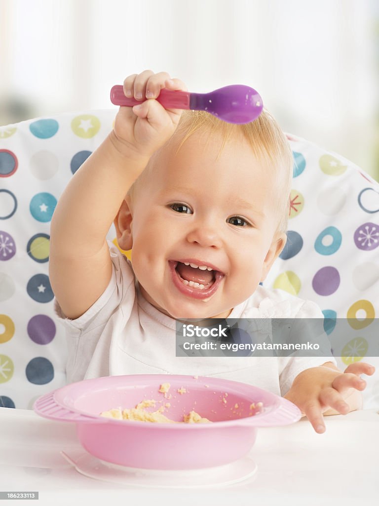 happy baby child eats itself with a spoon cheerful happy baby child eats itself with a spoon Baby - Human Age Stock Photo