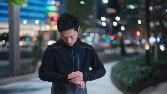 A male Asian athlete is running in the city at night.