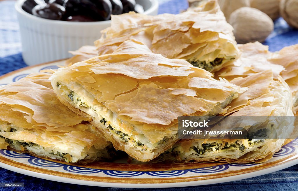 OPA! Spanakopita - Greek Spinach Pie with Olivess Spanakopita, Greek spinach pie with feta cheese and filo party on on plate with olives and walnuts on festive plate Spanakopita Stock Photo