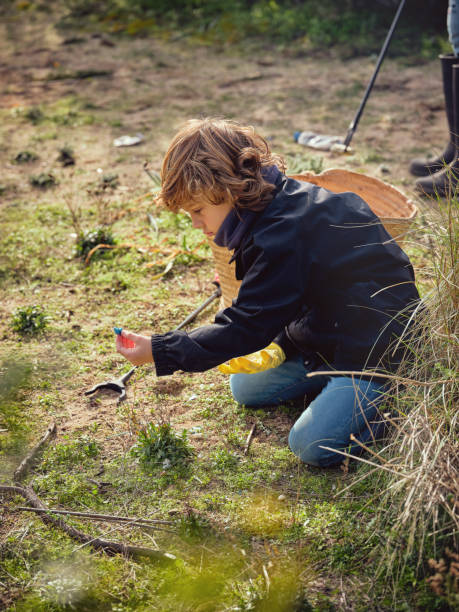 istock Concentrated preteen boy picking garbage on grassy ground 1862384110
