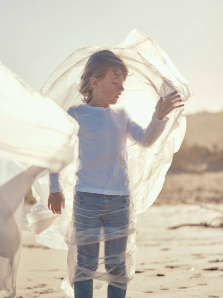 istock Preteen boy entangled in waving plastic sheet on sandy coast 1862386207