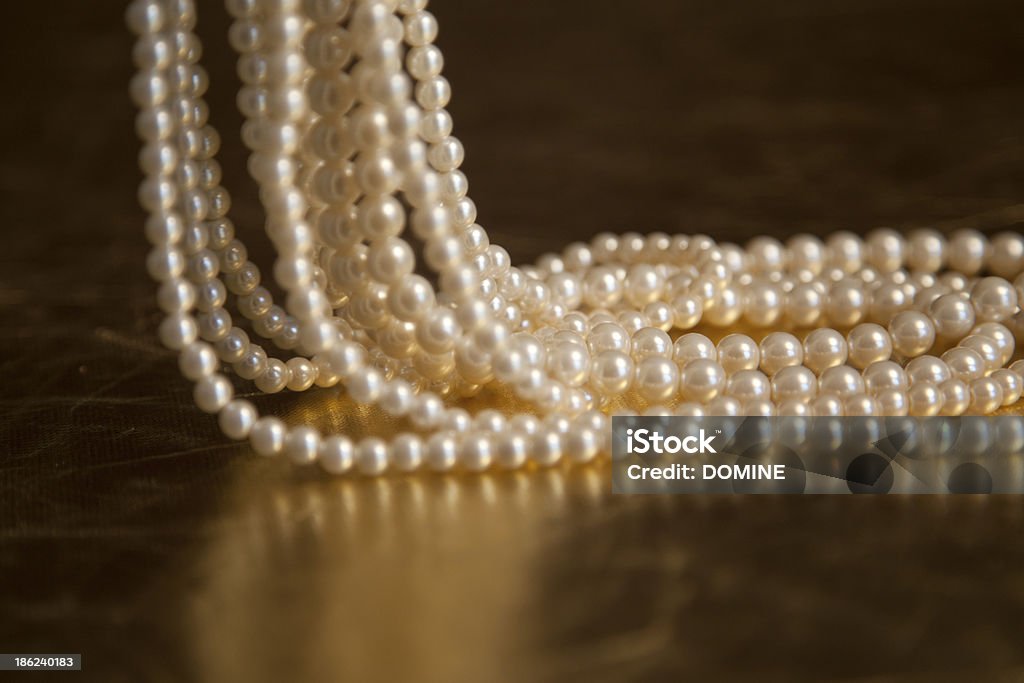 Pearls and necklace close up image of a pearl necklace. Shallow depth of field - the pearls are photographed on a gold leaf surface, natural warm colours are coming through. Abstract Stock Photo