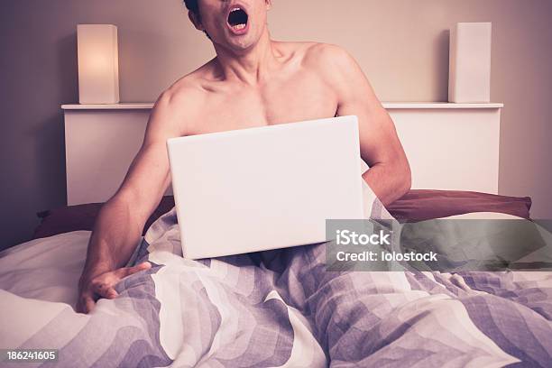 Young Man In Bed Watching Pornography On Laptop Stock Photo - Download Image Now - Pornography, Men, Bed - Furniture