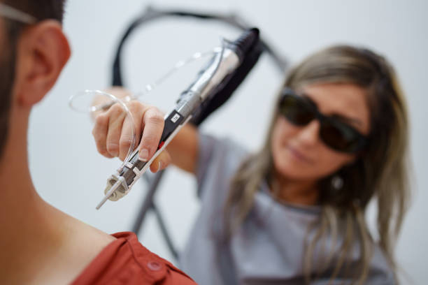 Man at the dermatology clinic for neck hair removal treatments Man at the dermatology clinic for hair removal treatments laser pen stock pictures, royalty-free photos & images